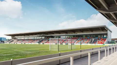 Computer-generated image of the pitch and one of the new stands at Cumberland Sports Village. A goal for football matches is at one end of the field. The stand, which has a mix of red and blue seating, has a roof.