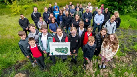 Bradford Council Group of children and adults standing by recently excavated wetland