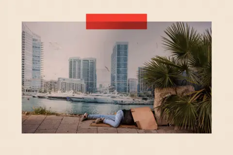 AFP via Getty Images A displaced man sleeps on a street next to a billboard showing Beirut's Marina 