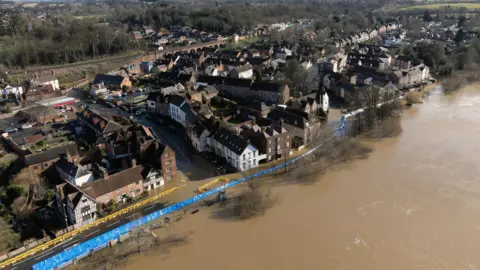 PA Media An aerial view of flooding in Bewdley as water from the River Severn breaches the food defences. Water can be seen on the roads next to houses with the blue-coloured flood defences along the river. 