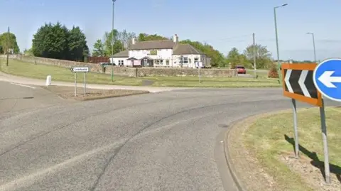 Google photograph of the A692 roundabout and its exit for Leadgate. A white two-storey pub building is in the background.