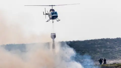 Pennine Helicopters Helicopter drops water on fire