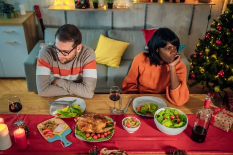 Young unhappy couple ignoring each other after an argument during Christmas dinner