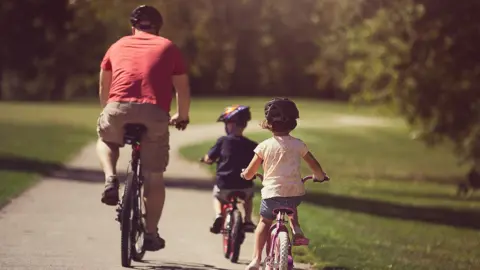 Getty A father with two children cycling on a path in a forest