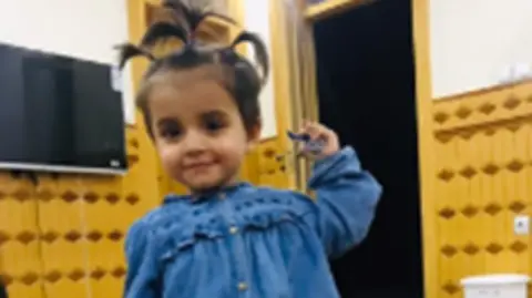 GMP Young child with bunches in her hair and blue denim dress.