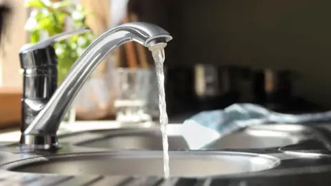 Stock image of water running from a stainless steel tap.