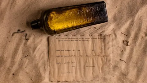 kymillman.com The bottle and the note placed on a sandy surface