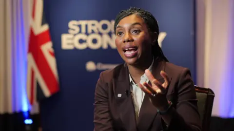 Kemi Badenoch wears an aubergine suit