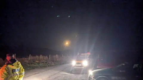 Rescue vehicles in the dark with some lights in the sky