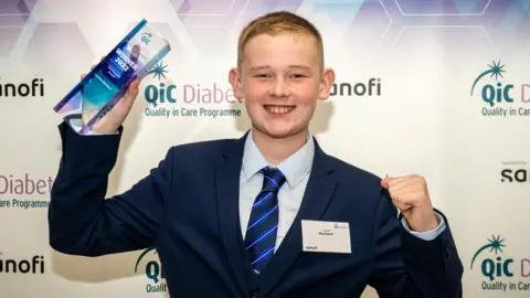 Lochlan Murdoch smiling, holding an award