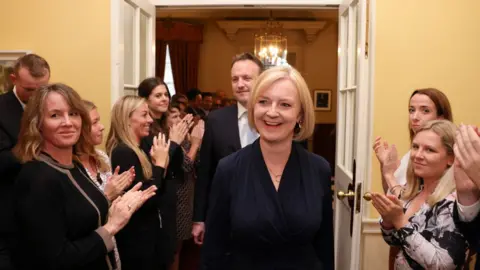 Andrew Parsons / No10 Downing Street Liz Truss and her husband are applauded as they walk through the corridor of 10 Downing Street