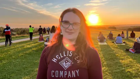 Holly Nichols/BBC Claire Laveaux stood in front of the sunrise