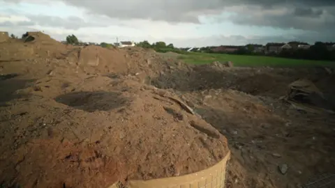 The aftermath of the crater is show - there is sand everywhere and a big hole in the ground