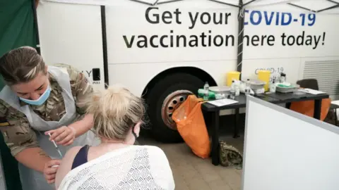 Getty Images A young woman is vaccinated by a medic from Queen Alexandra's Royal Army Nursing Corps outside Bolton Town Hall on 9 June