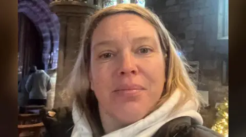 A close up of Amanda Hull in a church wearing a grey hoodie and a black jacket