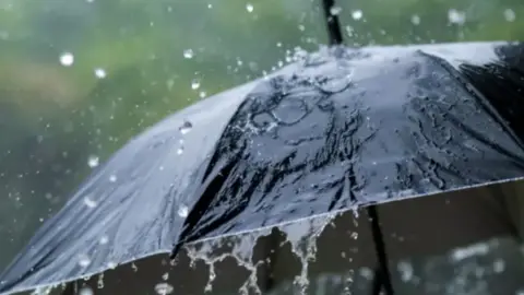 Getty Heavy rain falling onto a black umbrella
