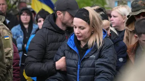 BBC/Lee Durant Serhii and Lilia, Maksym's parents, stand by his grave