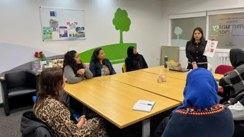 Dave Edwards/BBC A group of women sit around a table