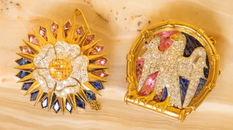 PA Media Two diamond-encrusted Cartier brooches depicting a falcon and a white Tudor rose.