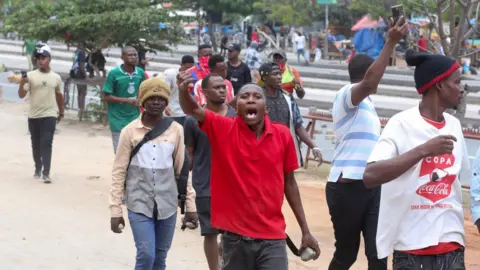 রয়টার্স ইয়ুথ নির্বাচন নিয়ে দার এস সালামে প্রতিবাদ করছে - একটি লাল টি-শার্টে একজন পাথর ধরে আছে - 29 অক্টোবর 2025।