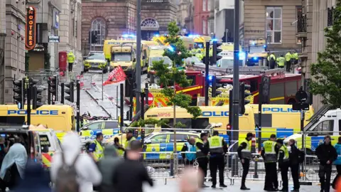 PA Media Dozens of emergency vehicles on Water Street, Liverpool, behind a police cordon after a car ploughed into a crowd of football fans.