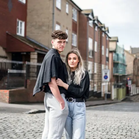 Lee Brodhurst-Hooper Portrait of a young couple standing in a street