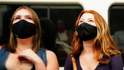 PA Media Two women in face masks on Tube train