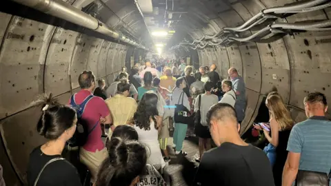 Twitter/PA Passengers walk along an emergency tunnel of the Channel Tunnel