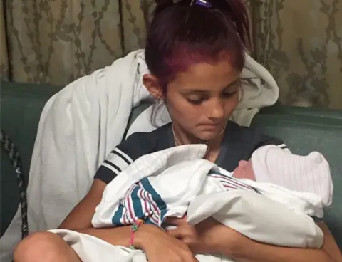 Nikki Smith Jacee, back in her civilian clothes, holds her new baby brother