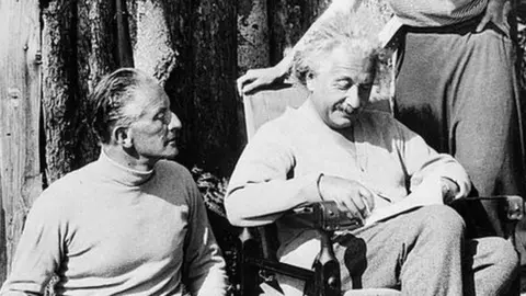 Albert Einstein with Oliver Locker-Lampson and secretary Miss B Howard under armed guard outside his log cabin in Roughton Heath, Norfolk