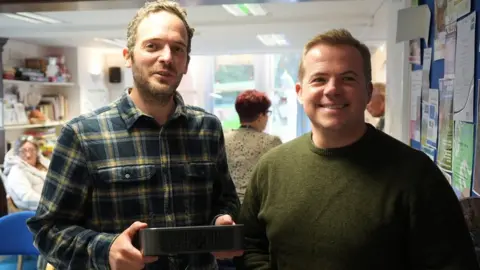 Jamie Niblock/BBC Dr Matt Ash and Dr James Brown holding a proto-type box