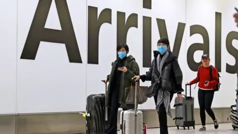 PA Media Passengers in the arrivals concourse at Heathrow Terminal 4, London