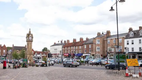 Getty Images A market town square with a large cobbled parking area and a clock tower