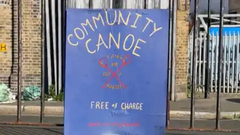 Lucy Acheson A blue sign reads 'Community Canoe Free of Charge' with a link to book the canoe on it.