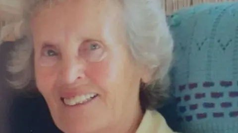 Family handout Jean Langan smiling and looking at the camera. She has short white hair and blue eyes and is wearing a yellow top.