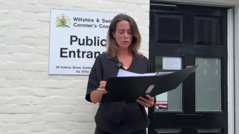 A woman outside a coroner's court reading out a statement from a booklet