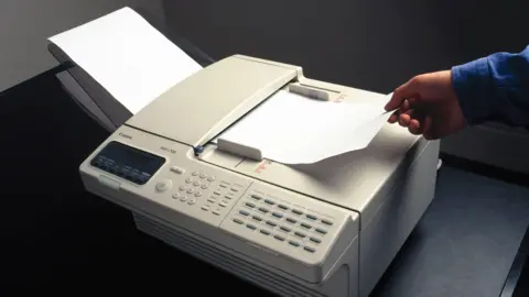 A man removes a piece of paper from a fax machine