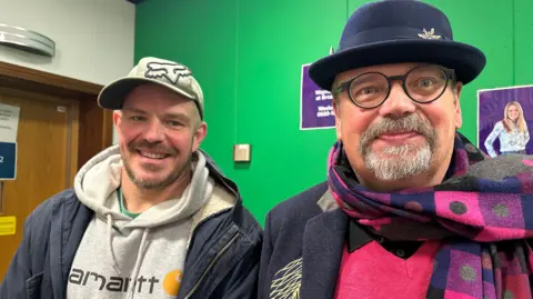 Dan Sedgewick and CB Jackson, both wearing hats, stand in the BBC Suffolk Green room.