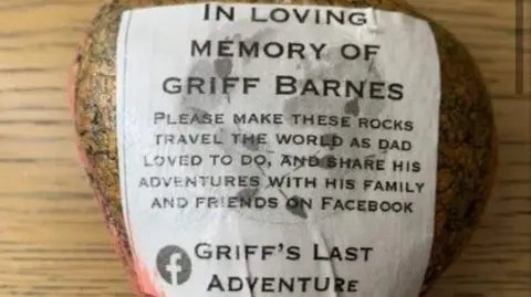 Izzy Barnes An image of a rock with a sticker on directing people who find it to go to the Facebook page