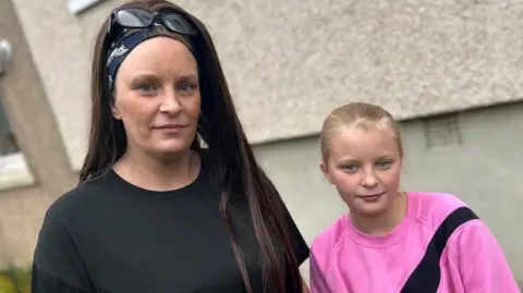 BBC Michelle in a black top standing next to her daughter Devon, dressed in a pink top