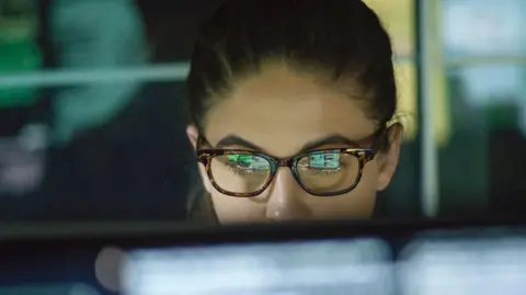 Close of of young woman wearing glasses looking at monitor