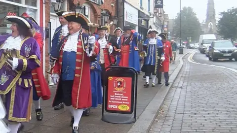 Eight of the town criers are included in the picture walking along a pavement in Sleaford in costume