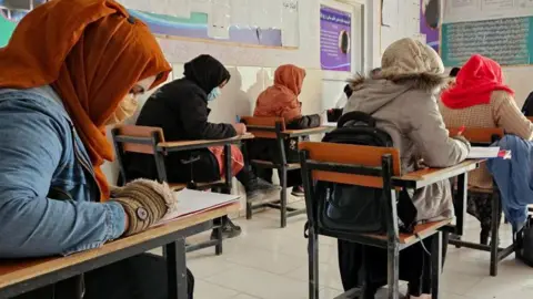 AFP Afghan women students, with their heads covered with colourful scarves, take a test in a classroom in Ghazni, Afghanistan on 10 December, 2024