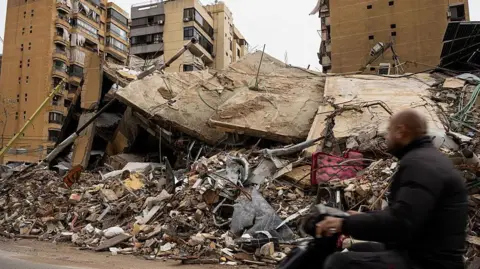 A motorcycle passes in front of buildings damaged after bombing in Beirut's Dahiyeh suburb 