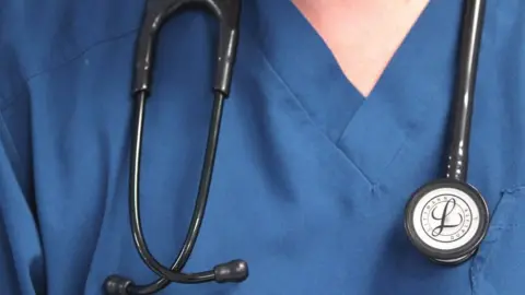 PA Media A generic, anonymous picture of a doctor in blue scrubs and wearing a stethoscope around their neck.