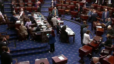 The Senate floor with people sitting in chairs