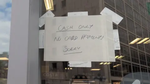 A sign on a Co-op shop reading "Cash only, no card payments, sorry"
