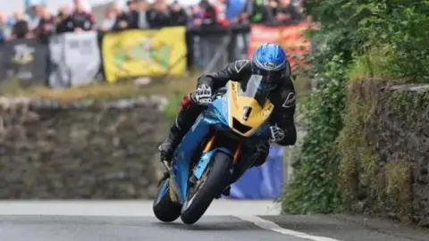 MANX GRAND PRIX Ingham racing in the MGP while crowds look on behind.