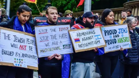 Getty Images Pro-Jewish supporters hold placards during the Pro-Jewish Rally organised by the Christian led "Never Again Is Now" movement to stand against hate and antisemitism and to support Jewish community. 