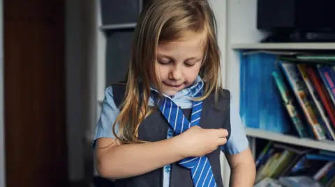 Getty Images A young girl tying her school tie